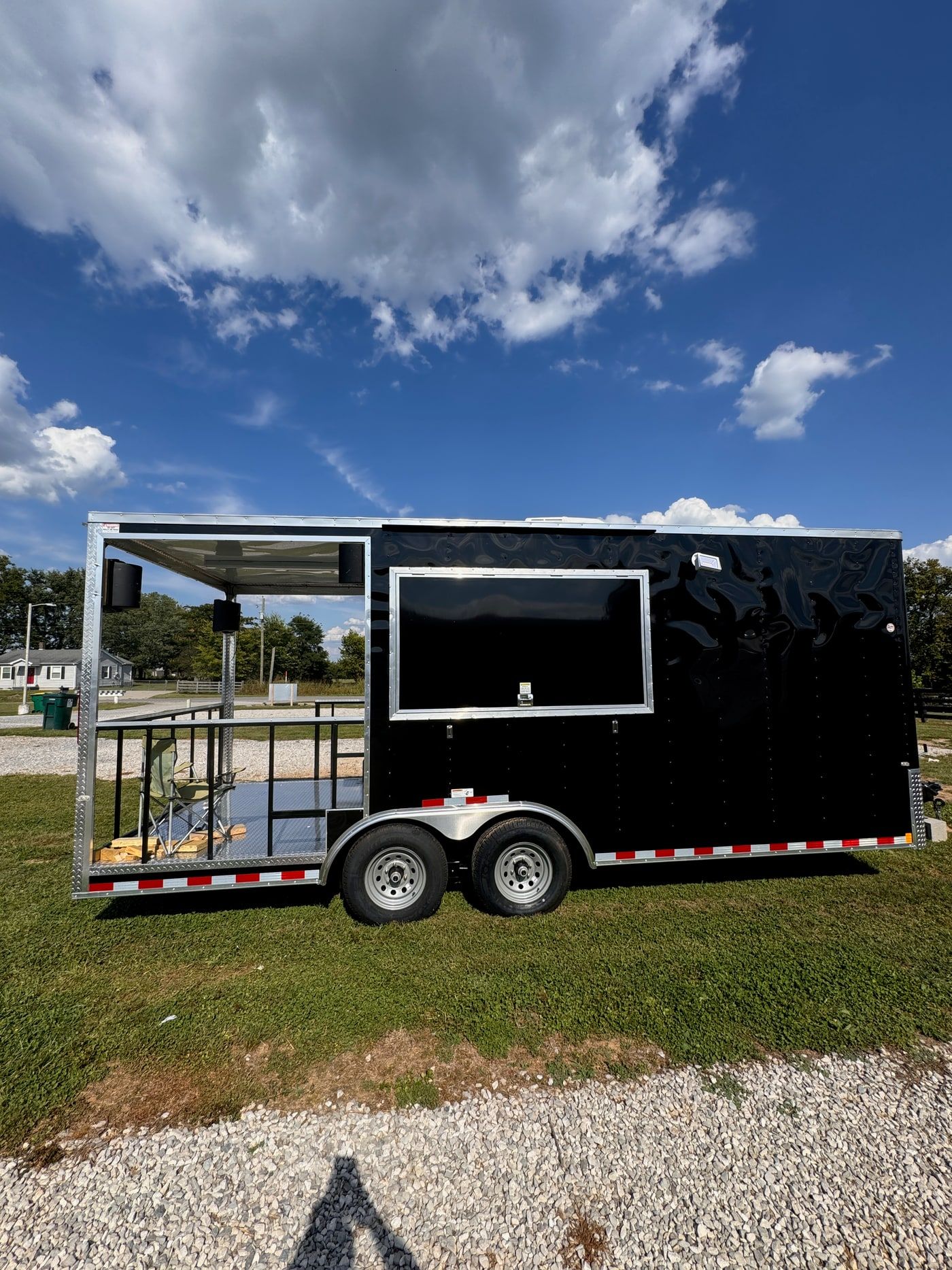 A custom auction and event trailer in gloss black, with a flip-down exterior display and speakers mounted under the awning.