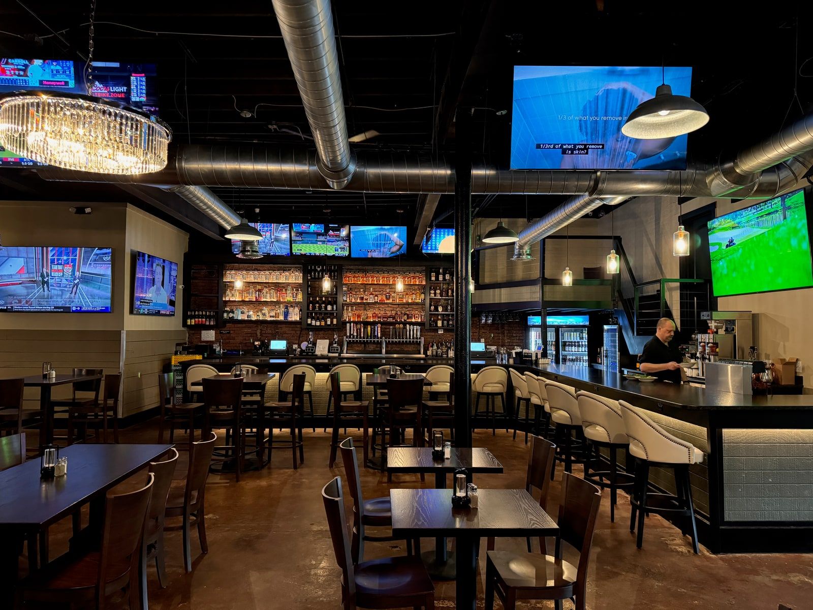 The back bar at Millstone Social with a wall of televisions tiled above the liquor shelves, each tuned to a different game.