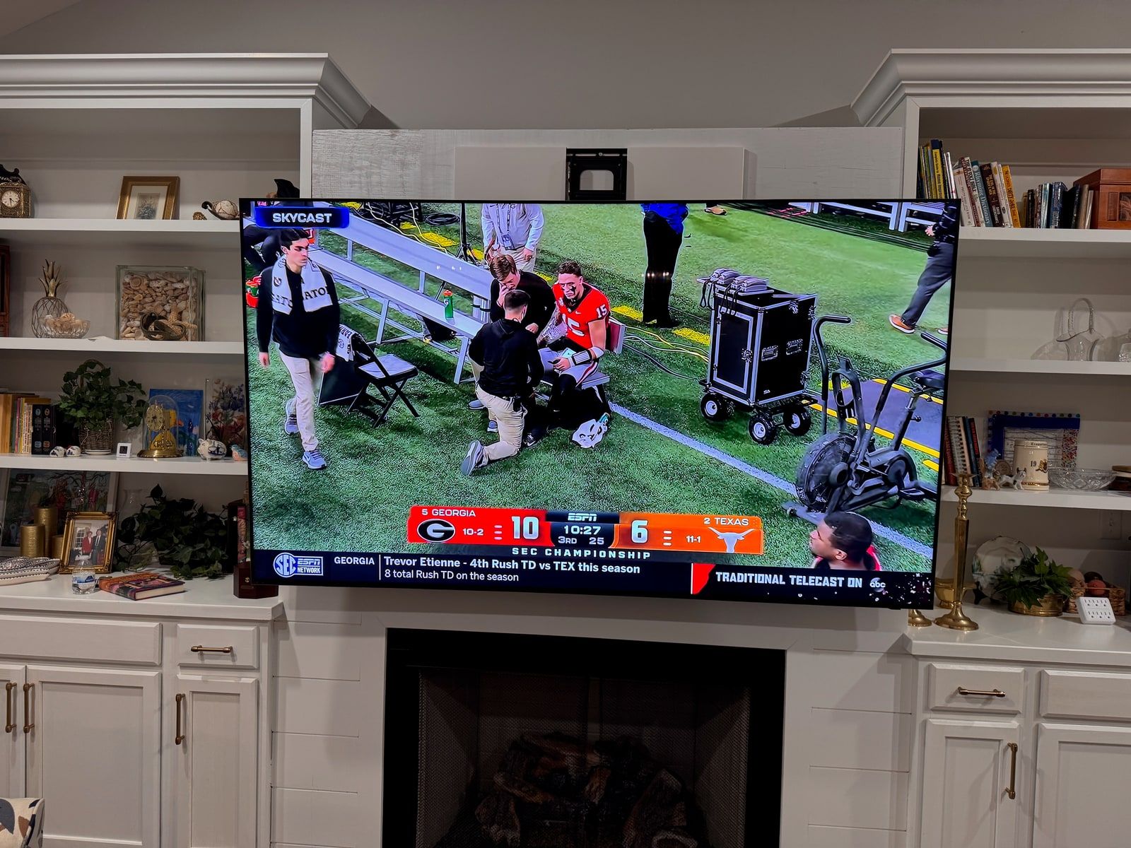 A television on a motorized mount displaying a live football broadcast, in use in a living room built-in.