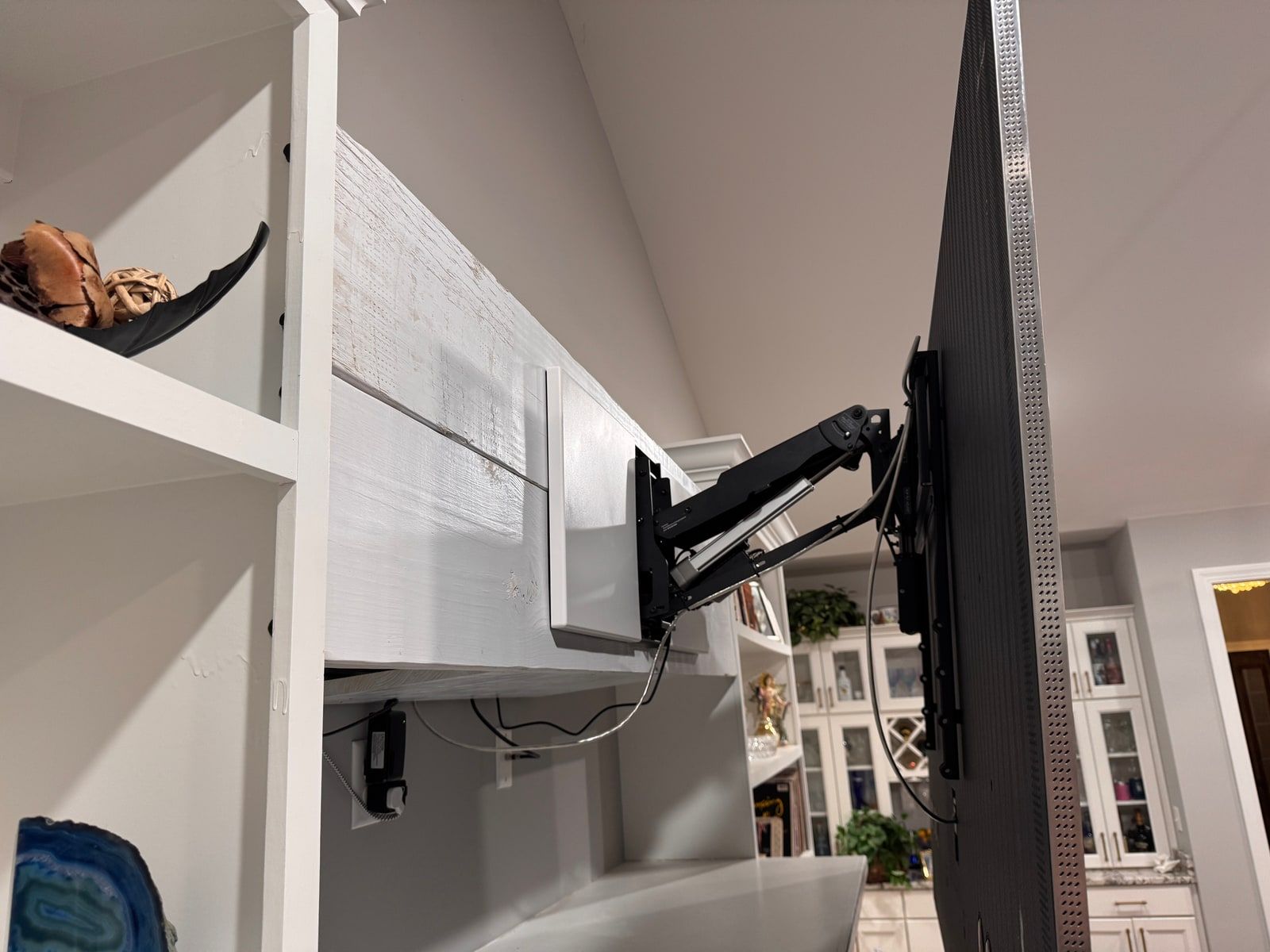 A motorized articulating TV mount fully extended from a built-in cabinet, swinging the display out into the room.
