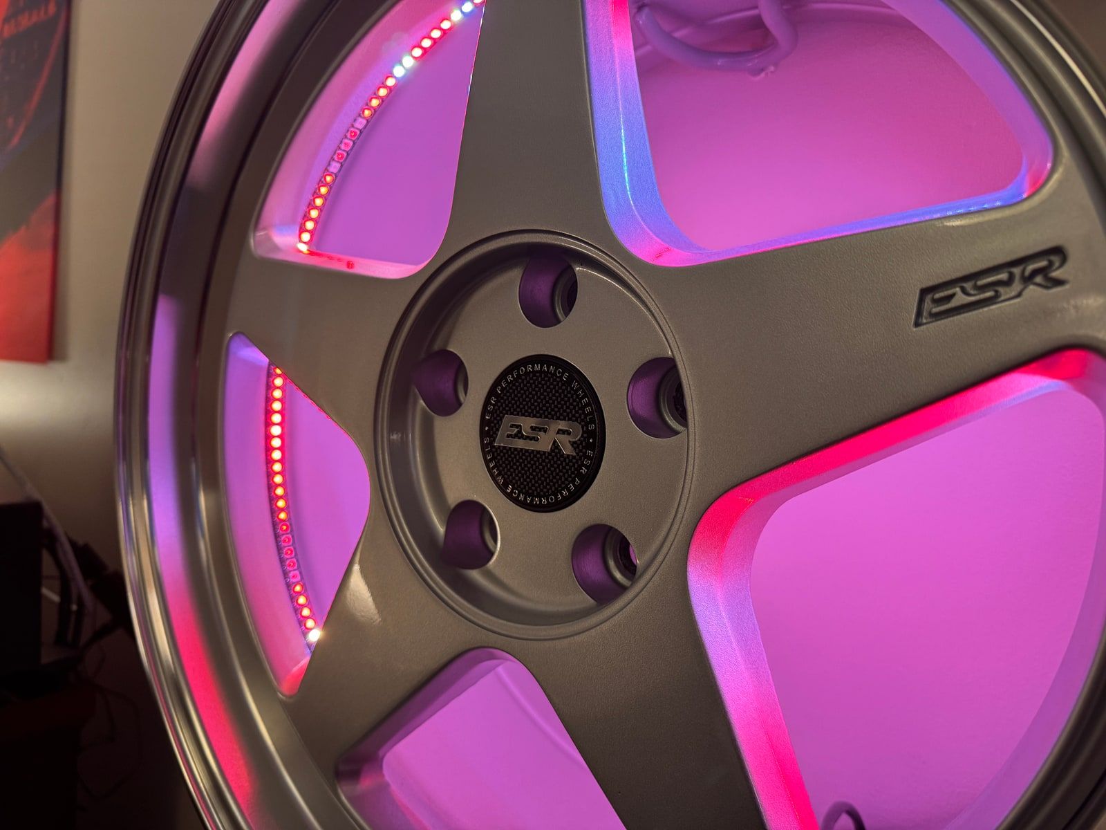 Macro shot of an RGB LED wheel diode strip lit in pink and red, showing individually addressable WLED lighting detail.
